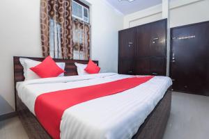 een slaapkamer met een groot bed met rode kussens bij OYO New Airport Residency in Jaipur