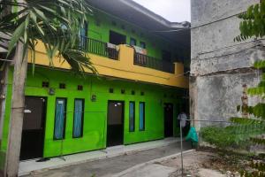 a green and yellow building with a balcony at OYO Life 93023 Kost Bulan Karawang in Karawang