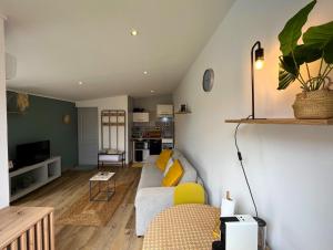 uma sala de estar com um sofá branco e almofadas amarelas em Charmant bungalow climatisé avec jacuzzi em Sainte-Clotilde