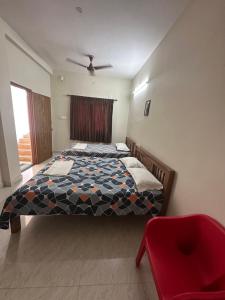 een slaapkamer met een bed en een rode stoel bij Jothi Residency in Madurai