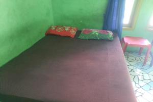 a bed with two pillows and a chair in a room at OYO Life 93023 Kost Bulan Karawang in Karawang