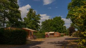 a group of small wooden cabins on a dirt road at Camping Vittel in Vittel