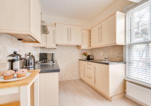 a kitchen with white cabinets and a sink at Butchers Loft in Saundersfoot