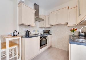 a kitchen with white cabinets and a sink at Butchers Loft in Saundersfoot