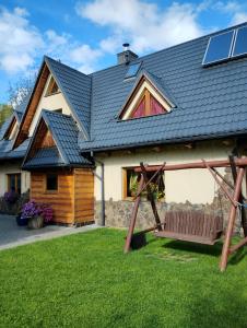 a house with a gambrel roof and a swing at Chatka Zuzia in Poronin