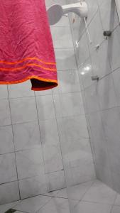 La salle de bains est pourvue d'une douche et d'une serviette rose. dans l'établissement Casa Frida 3, à Natal