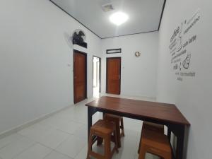 Home Syariah Guest House Ampana في Dondo: غرفة طعام مع طاولة وكراسي خشبية