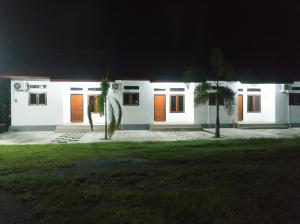 Home Syariah Guest House Ampana في Dondo: منزل أبيض مع أبواب برتقالية في الليل