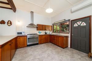 a kitchen with wooden cabinets and a black door at Rose Cottage Nannup in Nannup