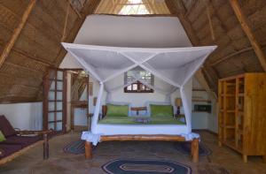 a bedroom with a bed in a thatched room at Belvedere Resort in Jambiani