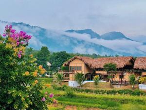 dom w polu z górami w tle w obiekcie Mai Chau Onsen Retreat w mieście Mai Châu