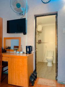 a bathroom with a desk with a toilet and a tv at Amy Hostel Hue in Hue