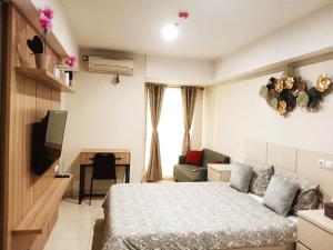 a bedroom with a bed and a desk and a television at Warhol Residence at Louise Kienne Simpang Lima Semarang in Semarang