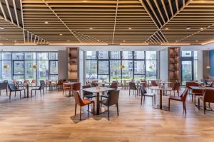 una sala da pranzo con tavoli, sedie e finestre di Holiday Inn Express Zhoukou Dancheng, an IHG Hotel a Zhoukou