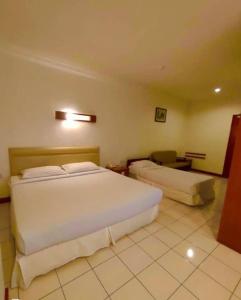 a bedroom with a large white bed and a couch at Theatreinn Sri Aman in Sri Aman
