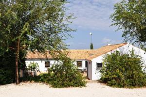 Biały dom z drzewami przed nim w obiekcie Casa rural La Liñana w Kordobie