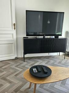 sala de estar con TV y mando a distancia sobre una mesa en Appartement Fernand Namur en Namur