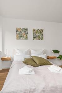 a white bedroom with a large white bed with green pillows at Studio-Apartment im Stadtzentrum in Bremen
