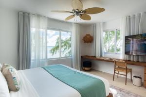 a bedroom with a bed and a desk and a fan at Seapoint Boutique Hotel in Pointe aux Cannoniers