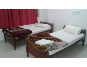 two twin beds in a room with a red curtain at Monika Guest House, Bodh Gaya in Bodh Gaya