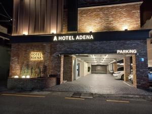 a hotel entrance with a parking garage at night at Adena Hotel in Busan
