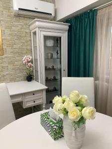 a white vase with white roses on a table at CHIC Apartment Piata Constitutiei - view from the balcony to the Palace of Parliament in Bucharest