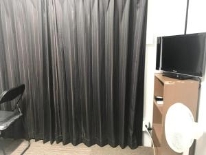 大阪市にあるNOW TRAVEL ShinOsakaのテレビ付きの部屋の黒いカーテン