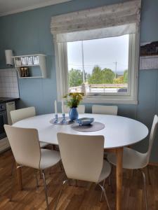une table à manger blanche avec des chaises blanches et une fenêtre dans l'établissement Idyllisk hus med sauna og jacuzzi, Lyngen, à Nord-Lenangen