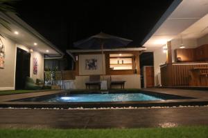 a swimming pool at night with an umbrella at BALE DATU BUNGALLOW in Gili Trawangan