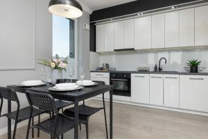 een keuken met een zwarte tafel en stoelen en witte kasten bij Podgórze Lipska Pet-friendly Apartment with Balcony and Parking by Renters Prestige in Krakau