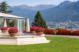 un groupe de fleurs en pot en face d'une maison dans l'établissement Villa Principe Leopoldo - Ticino Hotels Group, à Lugano