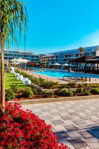 Un resort con piscina y algunas flores. en Courtyard Holiday Resort, en Saint Yeorgios