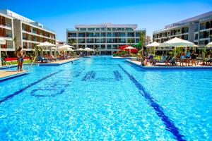 una gran piscina con sillas y sombrillas en Courtyard Holiday Resort, en Saint Yeorgios