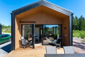 a small house with two chairs on a wooden deck at Himoskuutio 3 inc outdoor jacuzzi in Jämsä