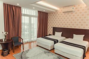 a hotel room with two beds and a desk and window at J&C HOTEL in Bắc Ninh