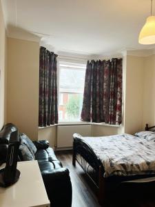a bedroom with a bed and a couch and a window at Nice and Pleasant in Thornton Heath