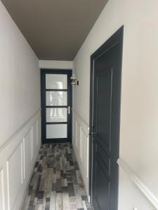 a hallway with a black door and a tile floor at Main de Bouddha et nonchalance in Arras