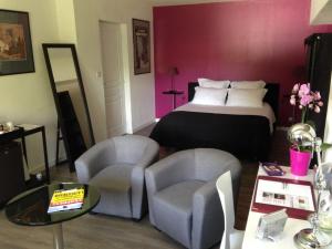 Habitación de hotel con 1 cama y 2 sillas en Les Chambres Lauryvan, en Saint-Junien