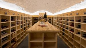 a wine cellar with a wooden table and shelves of wine bottles at Hotel Badhof in Altstätten