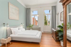 a bedroom with a white bed and two windows at Jugendstil-Traumwohnung direkt am Weserstadion in Bremen