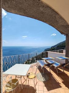 balcón con mesa, sillas y vistas al océano en Grand Hotel Excelsior, en Amalfi