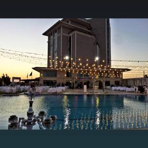 a building with a fountain in front of a building with lights at Burgaz İzer Hotel in Lüleburgaz