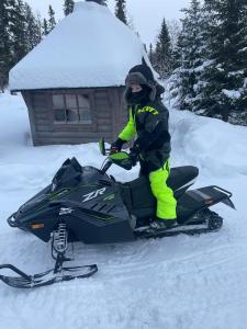 Eine Person steht auf einem Schneemobil im Schnee in der Unterkunft Ottsjö-Åre Lodge in Ottsjö