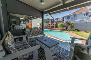 eine Terrasse mit Stühlen, einem Tisch und einem Pool in der Unterkunft Luxury Living On Westview in Port Elizabeth