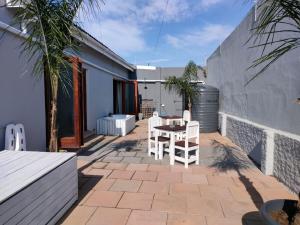 a patio with two white chairs and a table at Luxury Living On Westview in Port Elizabeth