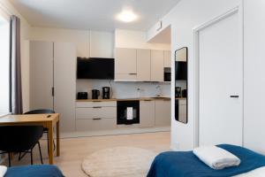 cocina con armarios blancos, mesa y cama en Forenom Serviced Apartments Pori Antinkatu en Pori