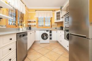 cocina con armarios blancos, lavadora y secadora en Country House Zambrana en Cártama