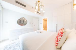 a white bedroom with a large bed and a mirror at Charming Brand New 2BR close to the Beach in Dubai