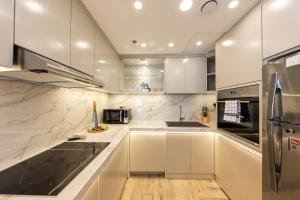 una cocina con armarios blancos y electrodomésticos de acero inoxidable en Charming Brand New 2BR close to the Beach en Dubái