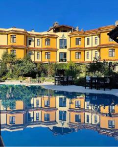 a yellow building with a reflection in a pool of water at Iliada Hotel Kaz Daglari in Kalkım